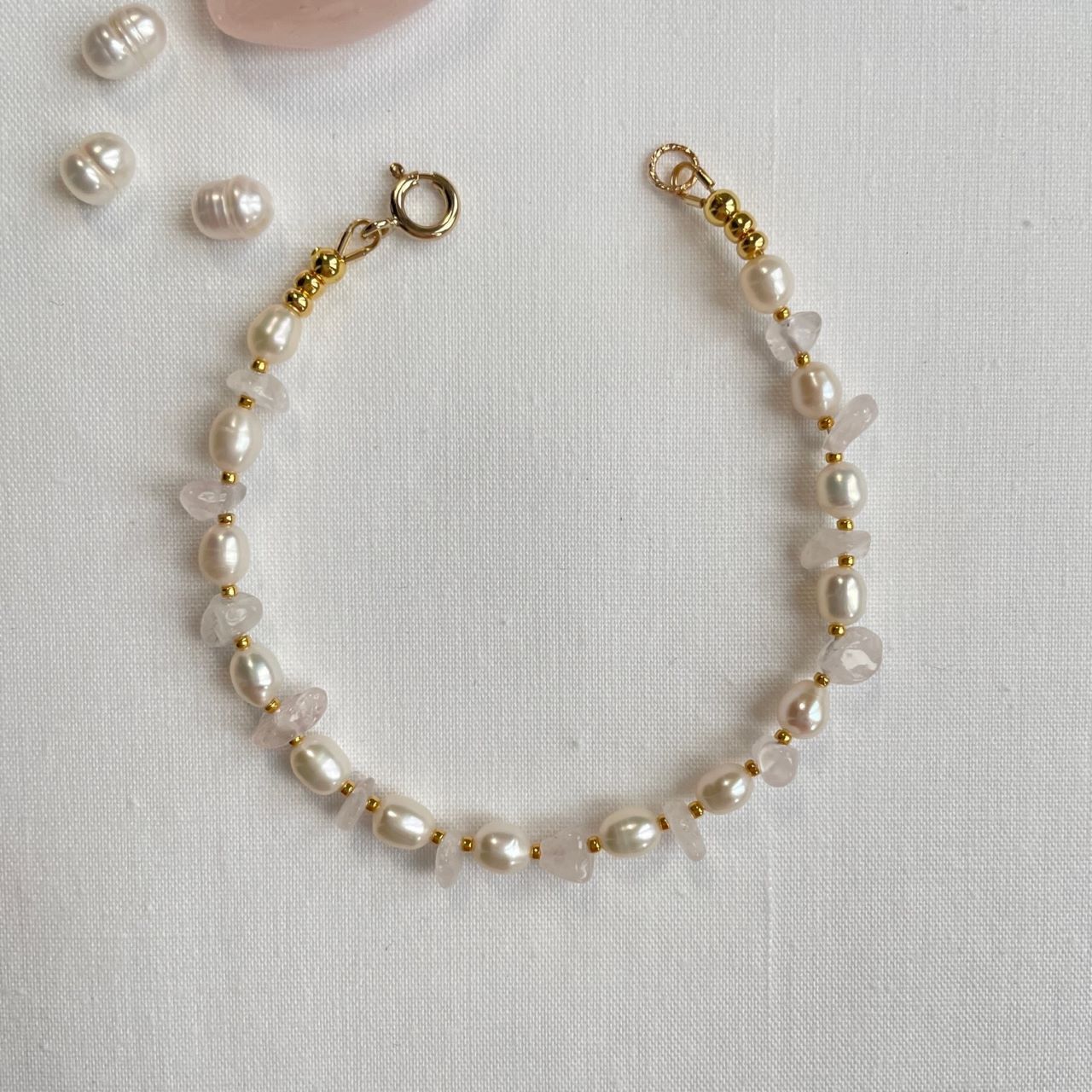 Dit armbandje is geregen van rozenkwartssplit en zoetwaterpareltjes met ertussen kleine 24K gold plated kraaltjes.&nbsp; Het armbandje heeft een lengte van 18.5 cm en sluit met een 14K gold filled veerslot.