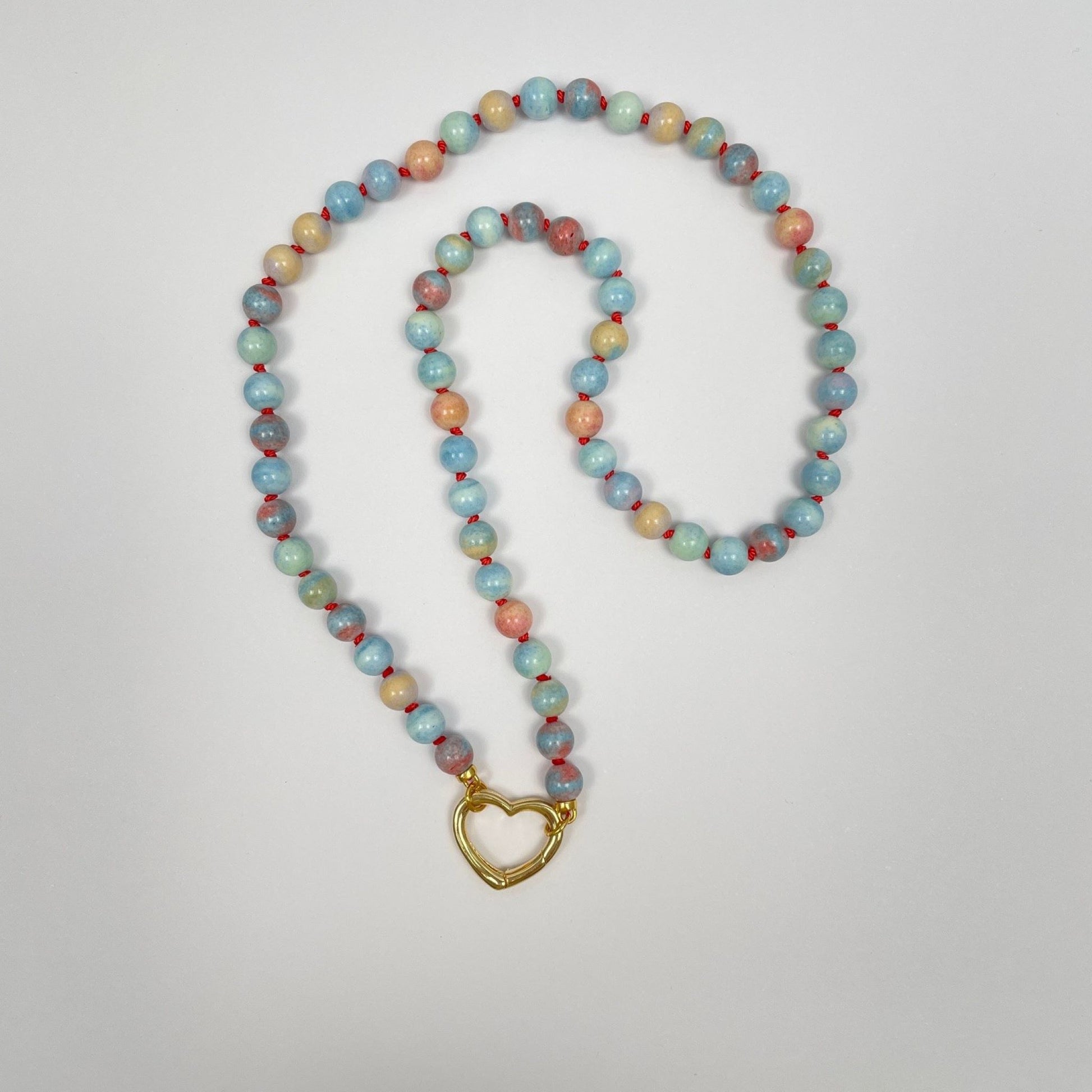 De ketting is geknoopt met koraalkleurige zijde van 6 mm kralen Mongoolse agaat. Deze kralen hebben veel verschillende lichte kleurtjes; blauw, groen, geel en oranje. De ketting eindigt met twee ringetjes waar een sluiting tussen kan worden gemaakt. Hier is dat een 18K gold filled hartje