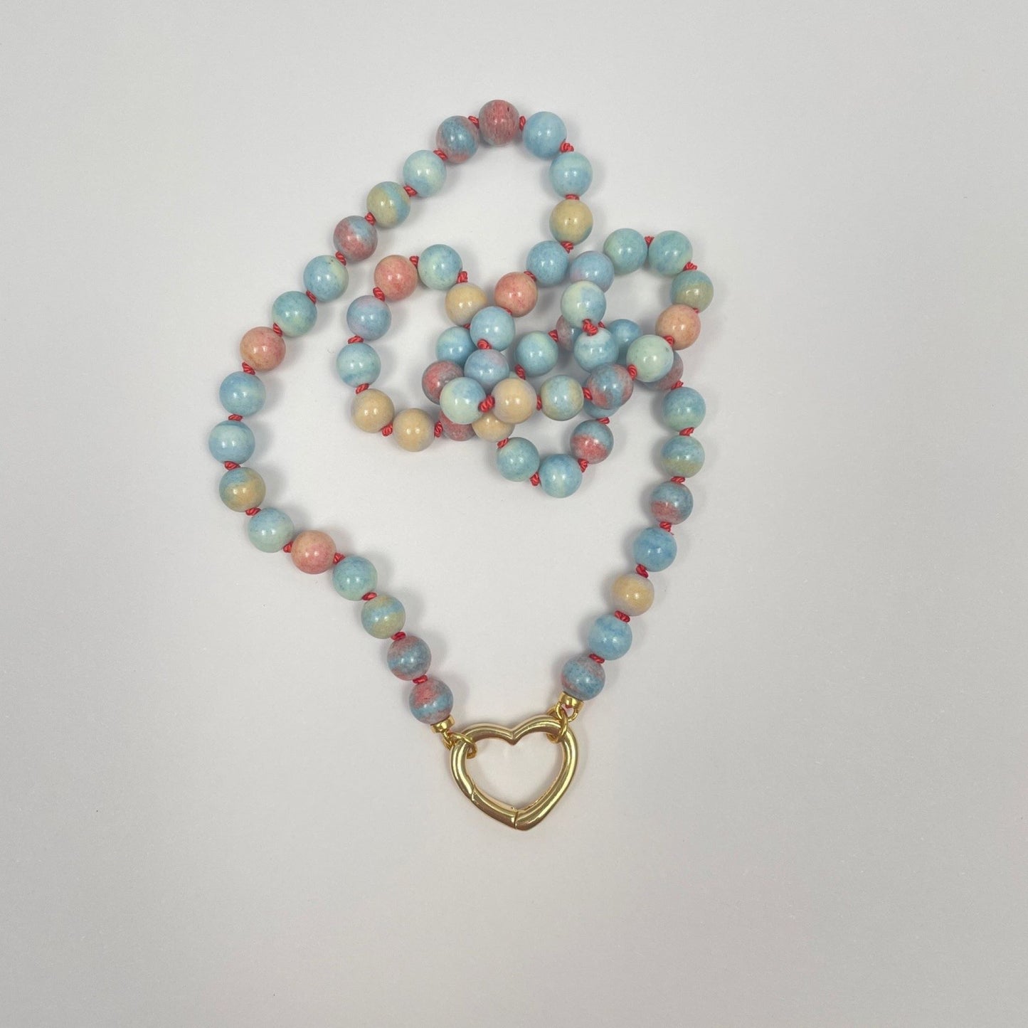 De ketting is geknoopt met koraalkleurige zijde van 6 mm kralen Mongoolse agaat. Deze kralen hebben veel verschillende lichte kleurtjes; blauw, groen, geel en oranje. De ketting eindigt met twee ringetjes waar een sluiting tussen kan worden gemaakt. Hier is dat een 18K gold filled hartje