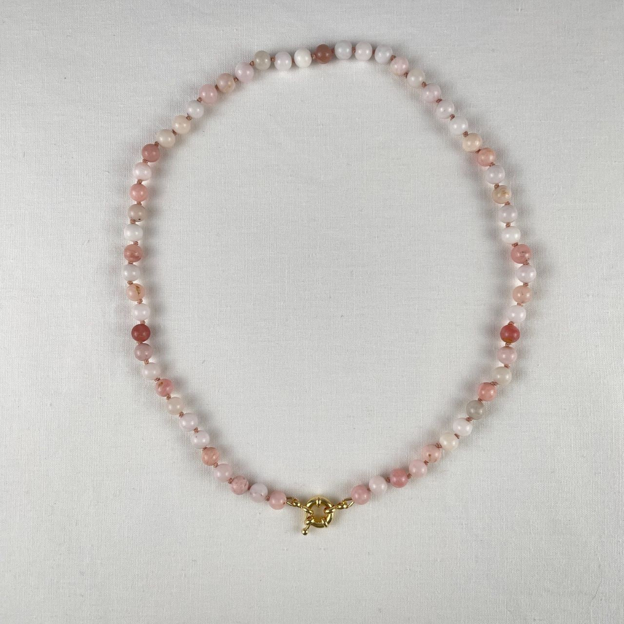 Deze ketting is geknoopt met lichtroze zijde en sluit met een 18K gold filled boeislot. De kralen zijn 6 mm roze Andes opaal kralen en hebben verschillende roze tinten die gaan van witachting naar donkerroze.