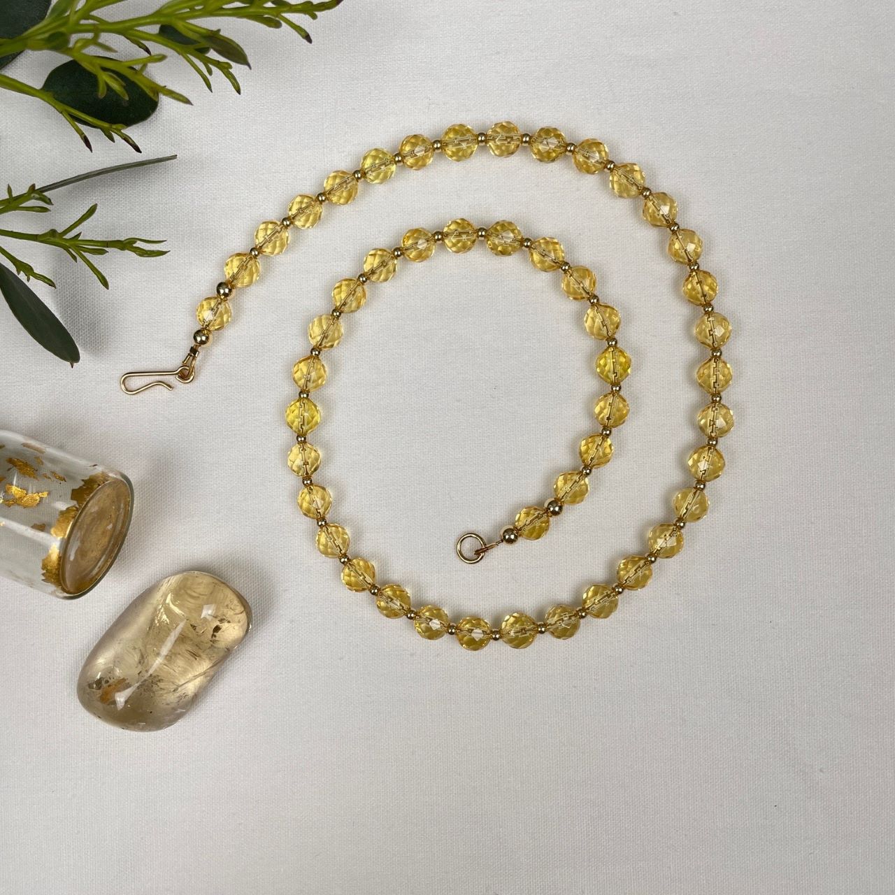 Ketting geregen van citrien facetkralen met heel veel facetjes en daartussen kleine gold filled kraaltjes. Afgewerkt met een paar grotere gold filled kraaltjes en een slotje in de vorm van een haakje.