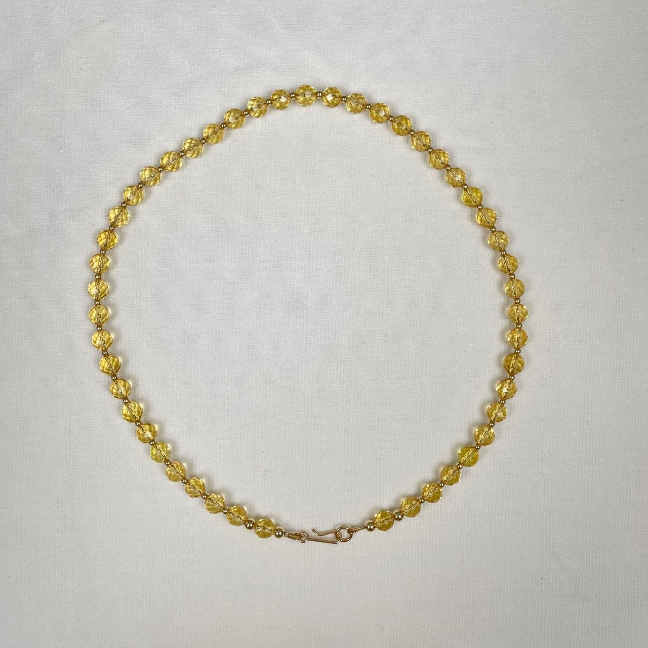 Ketting geregen van citrien facetkralen met heel veel facetjes en daartussen kleine gold filled kraaltjes. Afgewerkt met een paar grotere gold filled kraaltjes en een slotje in de vorm van een haakje.