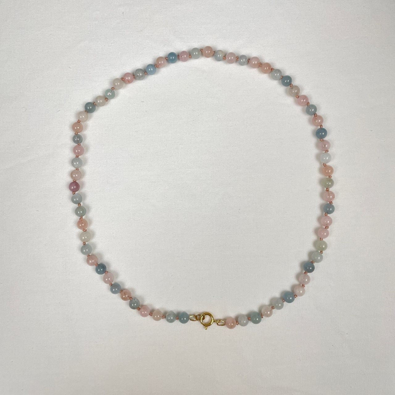 Deze ketting is dubbel geknoopt op lichtroze zijde en sluit met een 14K gold filled veerslotje. De kralen zijn 6 mm roze en lichtblauwe morganiet met aquamarijn kralen en hebben verschillende tinten: van witachting naar roze en blauw. 