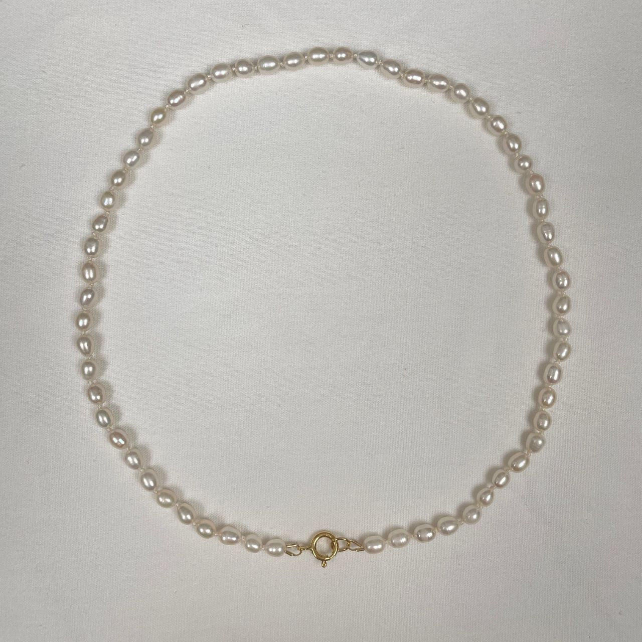 De zoetwaterpareltjes zijn geknoopt op een dubbele zijden draad. De parels hebben een rijstkorrelvorm en zijn 5 tot 6 mm lang. De ketting sluit met een decoratief gold filled veerslotje.