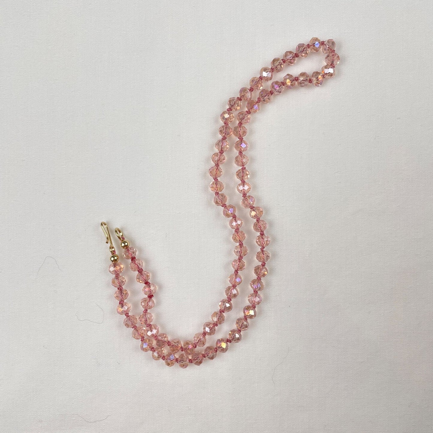 Deze ketting van roze facet kristal rondellen is geknoopt met roze zijde. Door de facetjes schittert de ketting je tegemoet en zie je allerlei kleuren zoals goud, lila en blauw. De ketting eindigt met een een paar gold filled kralen en sluit een gold filled haakje.