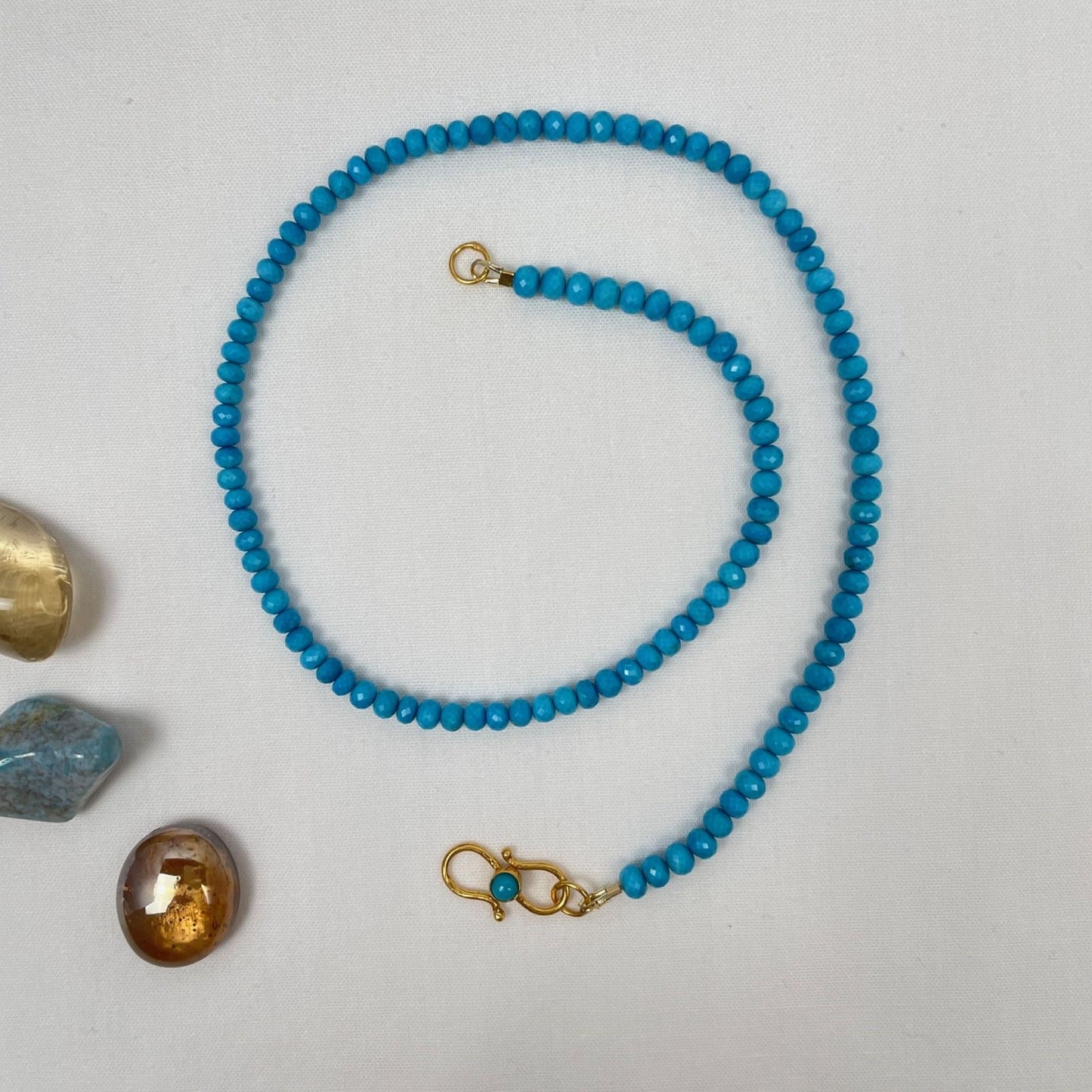 Ketting van turkoois 4 mm rondel facetkralen geregen op gecoat draad. De ketting is 43 cm en sluit met een vermeil siersluiting met een turkoois cabochon kraal. De sluiting kun je dus heel mooi voor dragen. De rondel kralen hebben heel kleine facetjes en lopen op en af in grootte. De grootste kralen zitten bij de sluiting.