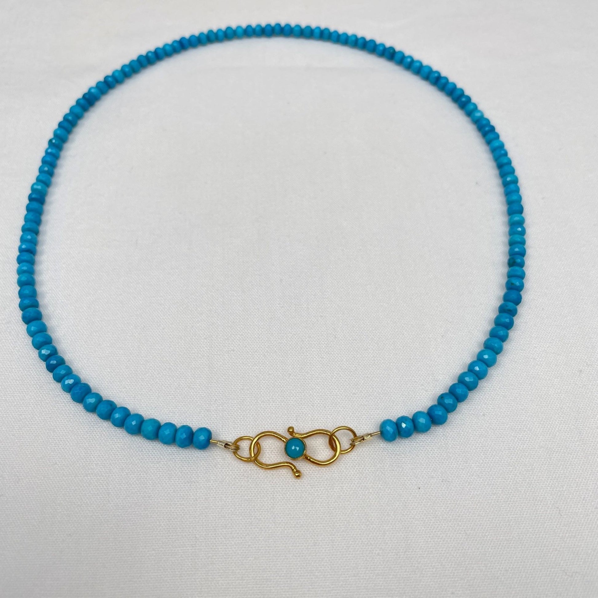 Ketting van turkoois 4 mm rondel facetkralen geregen op gecoat draad. De ketting is 43 cm en sluit met een vermeil siersluiting met een turkoois cabochon kraal. De sluiting kun je dus heel mooi voor dragen. De rondel kralen hebben heel kleine facetjes en lopen op en af in grootte. De grootste kralen zitten bij de sluiting.