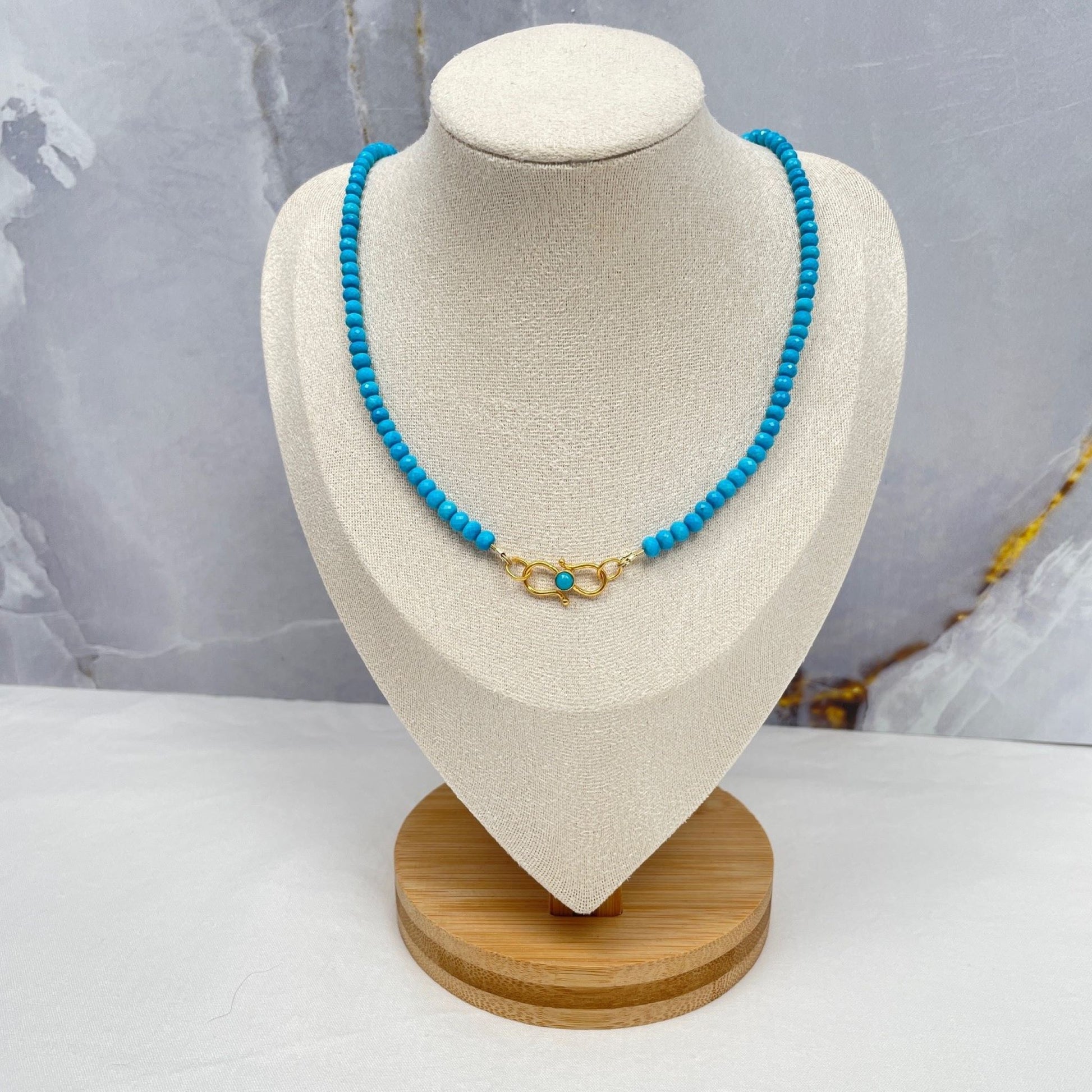 Ketting van turkoois 4 mm rondel facetkralen geregen op gecoat draad. De ketting is 43 cm en sluit met een vermeil siersluiting met een turkoois cabochon kraal. De sluiting kun je dus heel mooi voor dragen. De rondel kralen hebben heel kleine facetjes en lopen op en af in grootte. De grootste kralen zitten bij de sluiting. Hier hangt de ketting op een display.